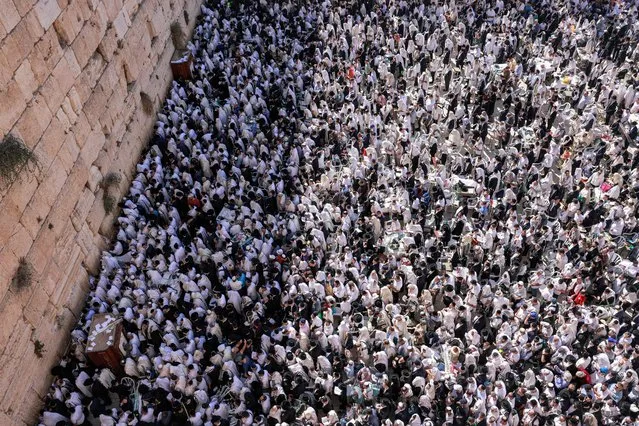 Jewish men, wearing traditional Jewish prayer shawls known as Tallit, gather at the Western Wall in the old city of Jerusalem on October 12, 2022 to perform the annual Cohanim prayer (priest's blessing) during the holiday of Sukkot, or the Feast of the Tabernacles. Thousands of Jews annually make the pilgrimage to Jerusalem during the week-long holiday of Sukkot, which commemorates the desert wanderings of the Israelites after their exodus from Egypt according to biblical tradition, and the gathering of the harvest. (Photo by Menahem Kahana/AFP Photo)