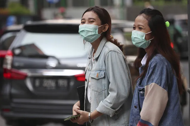People wear face masks as a precaution against the new coronavirus on a street in Jakarta, Indonesia Monday, June 8, 2020. Indonesia’s capital of Jakarta, the city hardest hit by the new coronavirus, has partly reopened after two months of partial lockdown as the world’s fourth most populous nation braces to gradually reopen its economy. (Photo by Achmad Ibrahim/AP Photo)