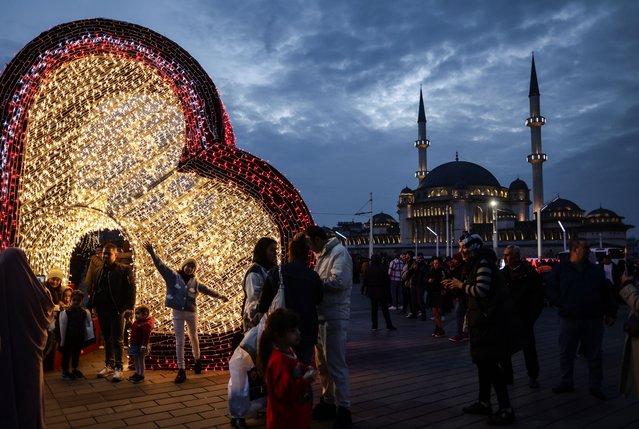 People take pictures with the light decorations prepared for the new year celebrations at the Taksim Square in front of the Taksim Mosque in Istanbul, Turkey, 31 December 2023. (Photo by Erdem Sahin/EPA)