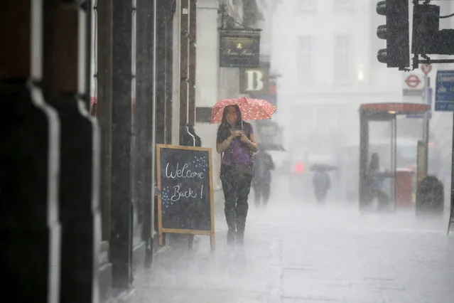 A woman wearing PPE (personal protective equipment), of a face mask or covering as a precautionary measure against COVID-19, shelters under an umbrella they are caught in a downpour of rain on Oxford Street in London on June 17, 2020, as lockdown restrictions imposed to stem the spread of the novel coronavirus continue to be relaxed. Britain's annual inflation rate slid to 0.5 percent in May, the lowest level in four years, as the country's coronavirus lockdown dampens prices, official data showed Wednesday. (Photo by Tolga Akmen/AFP Photo)