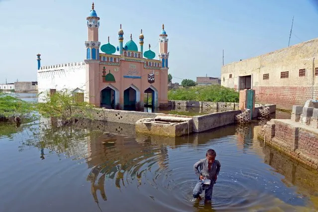 A boy wades through flood waters at Sohbatpur in Jaffarabad district of Balochistan province on September 19, 2022. (Photo by Fida Hussain/AFP Photo)