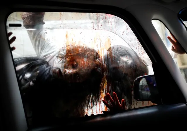 Actors dressed as zombies or ghouls perform during a drive-in haunted house show by Kowagarasetai (Scare Squad), for people inside a car in order to maintain social distancing amid the spread of the coronavirus disease (COVID-19), at a garage in Tokyo, Japan on July 3, 2020. (Photo by Issei Kato/Reuters)