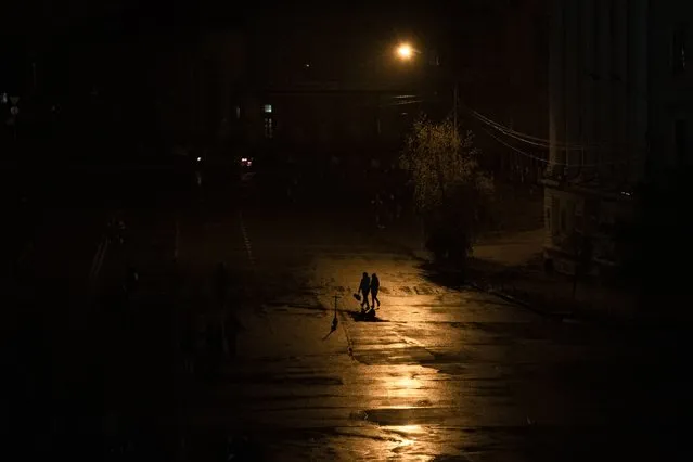 People walk across a street during a blackout in Kyiv, Ukraine, Sunday, November 6, 2022. (Photo by Andrew Kravchenko/AP Photo)