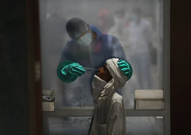 A health worker takes a nasal swab of a person for a COVID-19 test at a hospital in New Delhi, India, Monday, July 6, 2020. India has overtaken Russia to become the third worst-affected nation by the coronavirus pandemic. (Photo by Manish Swarup/AP Photo)