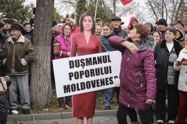 A woman slaps a cardboard cutout of Moldova's pro-western President Maia Sandu during a protest initiated by the populist Shor Party, calling for early elections and President Maia Sandu's resignation, in Chisinau, Moldova, Sunday, November 13, 2022. Thousands of anti-government protesters returned to the streets of Moldova's capital Sunday to express their dismay over alleged government failings amid an acute winter energy crisis and skyrocketing inflation. Banner reads “Enemy of the Moldovan people”. (Photo by Aurel Obreja/AP Photo)