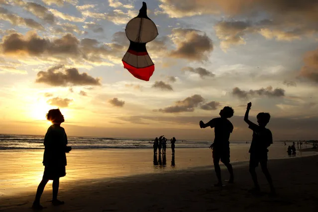 Boys fly their kite during sunset on Kuta beach in Bali, Indonesia, Friday, July 10, 2020. Indonesia's resort island of Bali reopened after a three-month virus lockdown Thursday, allowing local people and stranded foreign tourists to resume public activities before foreign arrivals resume in September. (Photo by Firdia Lisnawati/AP Photo)