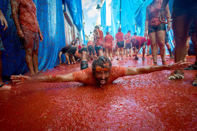 Revellers covered in tomato pulp participate in the annual “tomatina” festivities in the village of Bunol, near Valencia on August 31, 2016. (Photo by Biel Alino/AFP Photo)