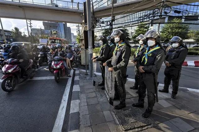 Police standing guard as commuters on motorbikes stop at a traffic signal near the venue of the Asia-Pacific Economic Cooperation (APEC) forum in Bangkok, Thailand, Tuesday, November 16, 2022. (Photo by Anupam Nath/AP Photo)