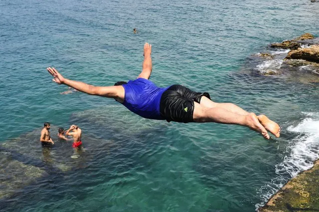 A man jumps into the water from the seaside promenade of Lebanon's capital Beirut on August 2, 2020. - New nationwide lockdown measures were announced last week following a rise in cases after previous restrictions were gradually lifted. To stem a larger outbreak, the government ordered a lockdown from July 30 through August 3, coinciding with the Muslim holiday of Eid al-Adha. (Photo by Anwar Amro/AFP Photo)