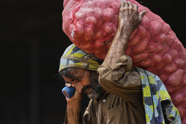 A laborer hauls a sack of potatoes to load into a mini truck at a wholesale vegetable market, in Islamabad, Pakistan, Thursday, May 1, 2025. (Photo by Anjum Naveed/AP Photo)