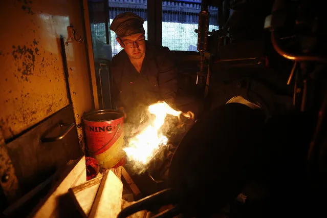 Puffing Billy trainee fireman Winston Martin lights a fire to put into the firebox of a steam locomotive, part of the four-hour-long process to prepare the engine, at Belgrave near Melbourne, October 20, 2014. (Photo by Jason Reed/Reuters)