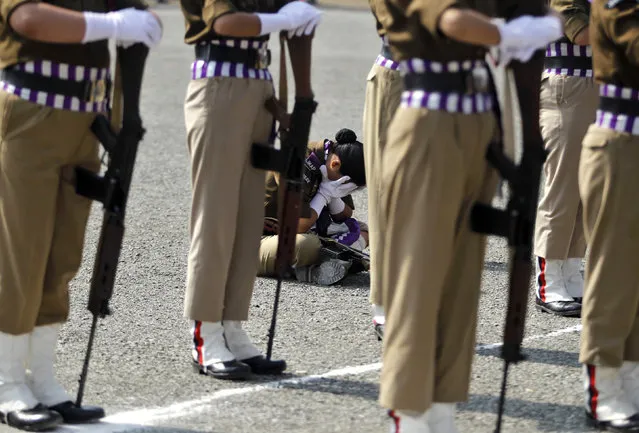 A member of a female police contingent holds her face in her hands as she sits during a parade to mark Police Commemoration Day in Zewan, on the outskirts of Srinagar, October 21, 2014. (Photo by Danish Ismail/Reuters)