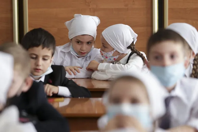 Pupils wearing face masks to protect against coronavirus sit in a classroom during a ceremony marking the start of classes at a school as part of the traditional opening of the school year known as “Day of Knowledge” in Grozny, Russia, Tuesday, September 1, 2020. Across the country, schools start their usually festive opening day on Sept. 1. (Photo by Musa Sadulayev/AP Photo)