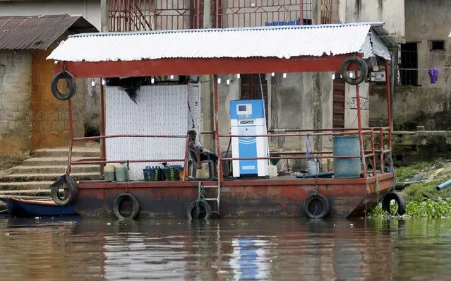 A petrol attendant sits on a floating fuel station on the banks of the Nun River on the outskirts of the Bayelsa state capital, Yenagoa, in Nigeria's delta region October 8, 2015. (Photo by Akintunde Akinleye/Reuters)