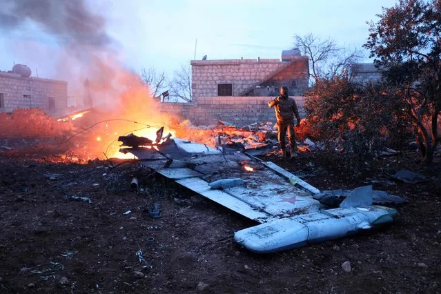 A picture taken on February 3, 2018, shows a Rebel fighter taking a picture of a downed Sukhoi-25 fighter jet in Syria' s northwest province of Idlib. Rebel fighters shot down a Russian plane over Syria' s northwest Idlib province and captured its pilot, the Syrian Observatory for Human Rights said. (Photo by Omar Haj Kadour/AFP Photo)