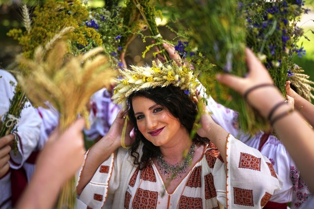 Women, wearing crowns made of flowers, dance during an event inspired by pre-Christian traditions, in which fairies, called in Romanian “Sanziene”, come to earth around the summer solstice bringing fertility to land and beings, at the Dimitrie Gusti Village Museum in Bucharest, Romania, Tuesday, June 24, 2025. (Photo by Andreea Alexandru/AP Photo)