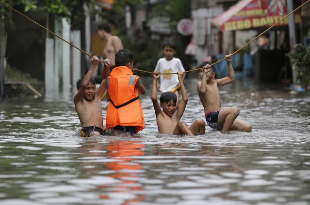 Boys play outside their flooded homes after heavy rains from tropical storm Gorio flooded parts of metropolitan Manila, Philippines on Thursday, July 27, 2017. Strong rains caused floods in low-lying areas and classes were suspended in most schools in the capital. (Photo by Aaron Favila/AP Photo)