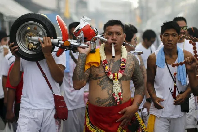 A devotee of the Chinese Bang Neow shrine walks with a motorcycle handlebar pierced through his cheek during a procession celebrating the annual vegetarian festival in Phuket, Thailand October 18, 2015. (Photo by Jorge Silva/Reuters)