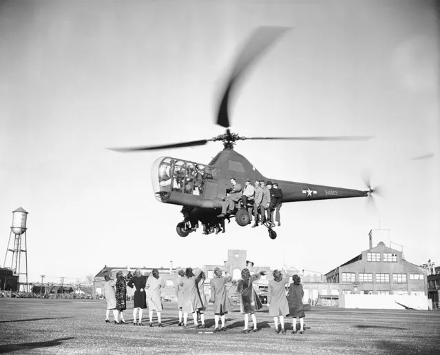 An Army Sikorsky R-5 helicopter, undergoing record trials, demonstrates its lifting power by carrying 17 persons and pilot aloft as female onlookers wave in Bridgeport, Conn., January 10, 1946. During the tests records were claimed for altitude speed and both altitude and speed with payload. (Photo by Anthony Camerano/AP Photo)