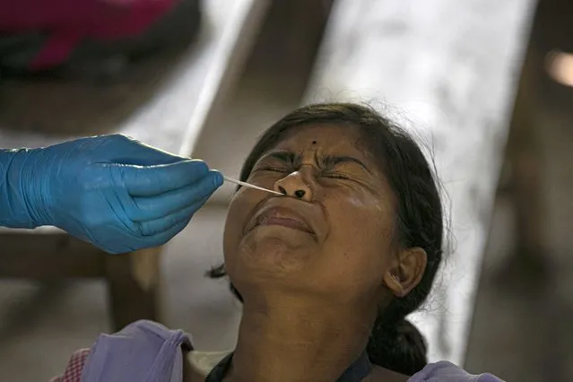 An Indian health worker takes a nasal swab sample of a student to test for coronavirus after classes started at a college in Jhargaon village, outskirts of Gauhati, India, Wednesday, September 30, 2020. India's Health Ministry on Wednesday raised its confirmed total of coronavirus cases to more than 6.2 million. (Photo by Anupam Nath/AP Photo)