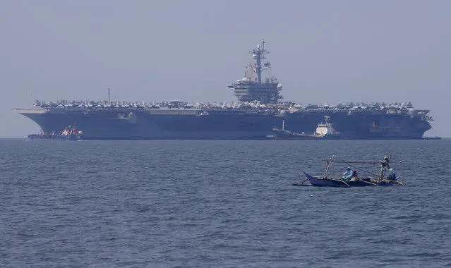 In this February 17, 2018, file photo, fishermen on board a small boat pass by the USS Carl Vinson aircraft carrier at anchor off Manila, Philippines, for a five-day port call. The USS Carl Vinson will reportedly make a historic visit to Vietnam in March 2018 as part of the Navy’s largest multinational disaster response exercises in the Indo-Pacific region. (Photo by Bullit Marquez/AP Photo)