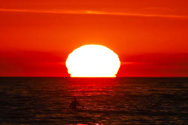 A surfer waits for a wave as the sun sets over the horizon Wednesday, December 27, 2017, in Pacific Palisades, Calif. (Photo by Jae C. Hong/AP Photo)