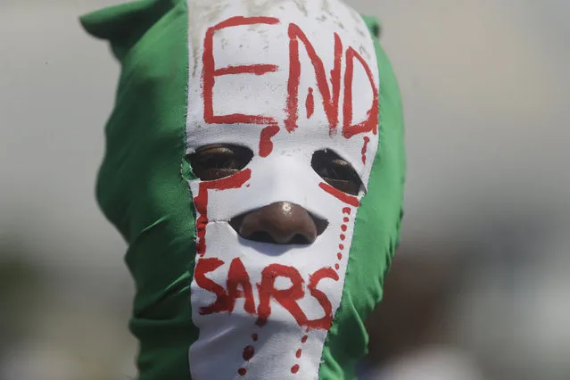 People demonstrate on the street to protest against police brutality, in Lagos, Nigeria, Sunday October 18, 2020. Nigerian protests against police brutality continued Sunday for the eleventh day, with demonstrators fending off attacks from gangs suspected to be backed by the police, warnings from the Nigerian military, and a government order to stop because of COVID-19. (Photo by Sunday Alamba/AP Photo)