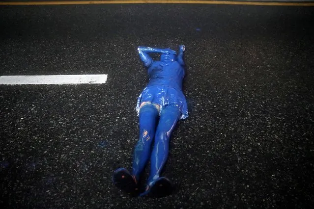 A pro-democracy activist covered in blue paint lies on the ground during an anti-government protest, in Bangkok, Thailand on October 17, 2020. (Photo by Soe Zeya Tun/Reuters)