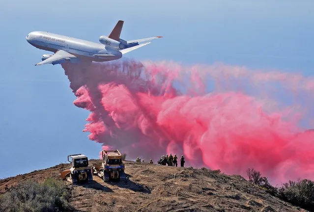 A DC-10 air tanker drops phos-check on the Gibraltar Fire as firefighters watch from a peak in the Los Padres National Forest above Santa Barbara, California in this handout photo from the Santa Barbara County Fire Department released to Reuters October 29, 2015. The fire burned about 50 acres but had firefighters on high alert as hot, dry Santa Ana winds have returned to southern California. (Photo by Mike Eliason/Reuters/Santa Barbara County Fire Department)