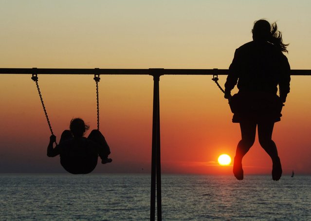 The sun sets along Lake Michigan as two people enjoy the swings at Silver Beach in St. Joseph, Mich., Thursday, June 19, 2025. (Photo by USA Today)