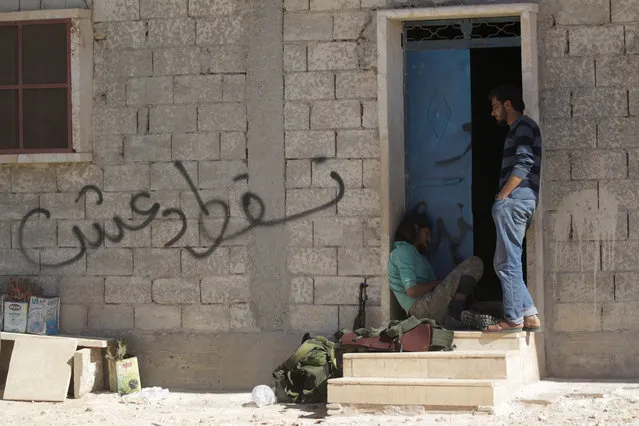 Rebel fighters rest near graffiti on a wall which reads in Arabic “Down with Daesh” in Akhtarin town, northern Aleppo countryside, Syria October 16, 2016. (Photo by Khalil Ashawi/Reuters)