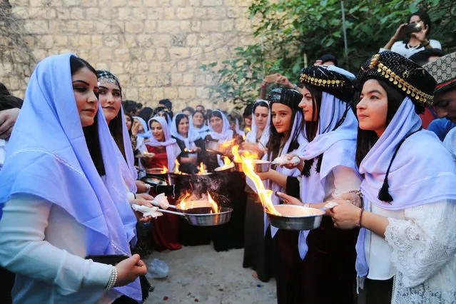 Iraqi Yazidis light candles and paraffin torches during a ceremony to celebrate the Yazidi New Year at Lalish temple in Shikhan in Dohuk province, Iraq on April 17, 2018. (Photo by Ari Jalal/Reuters)