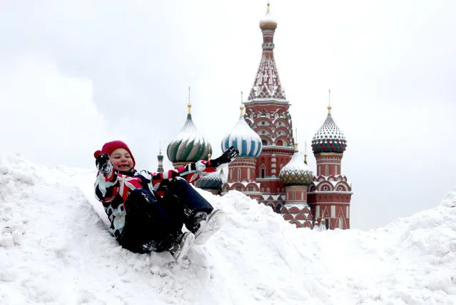 A child slides down a snow drift in Red Square in Moscow, Russia on December 15, 2020. (Photo by Valery Sharifulin/TASS)