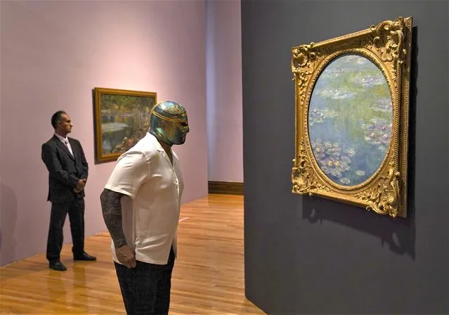 A Mexican Lucha Libre wrestler named CintaDeOro observes a painting by Claude Monet during the inauguration of a Monet exhibition at the National Arts Museum in Mexico City, Wednesday, April 26, 2023. (Photo by Fernando Llano/AP Photo)