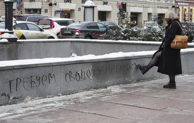 A woman writes with her foot on a frosty barrier in Russian “We demand freedom for Navalny” in St.Petersburg, Russia, Monday, January 18, 2021. Russian opposition leader Alexei Navalny was detained at passport control at Moscow's Sheremetyevo airport after flying in Sunday evening from Berlin, where he was treated following the poisoning in August that he blames on the Kremlin. (Photo by Dmitri Lovetsky/AP Photo)