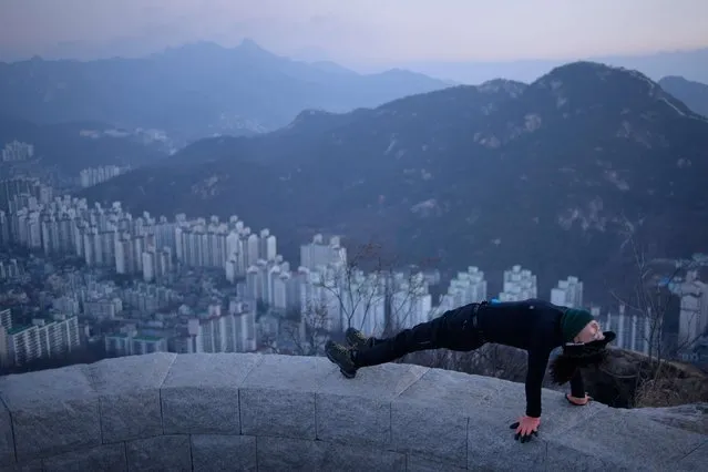 In a photo taken early on January 11, 2015 a hiker stretches at a viewpoint overlooking the Seoul city skyline. Early morning hikers and photographers are a familiar sight across the city's many viewpoints. (Photo by Ed Jones/AFP Photo)