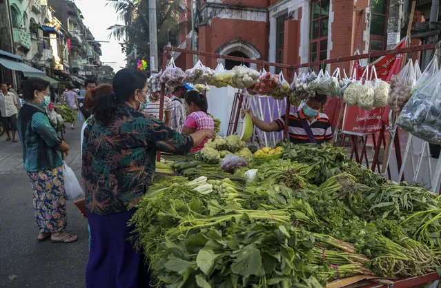 A woman buys vegetable in a street market Yangon, Myanmar, Tuesday, February 2, 2021. Hundreds of members of Myanmar's Parliament remained confined inside their government housing in the country's capital on Tuesday, a day after the military staged a coup and detained senior politicians including Nobel laureate and de facto leader Aung San Suu Kyi. (Photo by Thein Zaw/AP Photo)