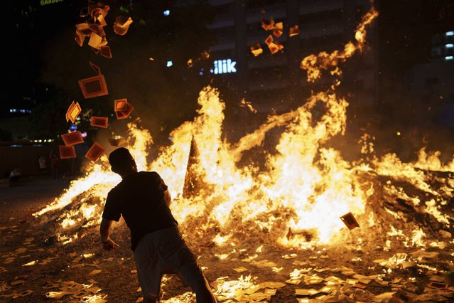 Ethnic Chinese throw paper offerings during the burning of a giant paper statue of the Chinese deity "Da Shi Ye" or ”Guardian God of Ghosts” during the Chinese Hungry Ghost Festival in Kuala Lumpur, Malaysia, Sunday, September 7, 2025. (Photo by Vincent Thian/AP Photo)