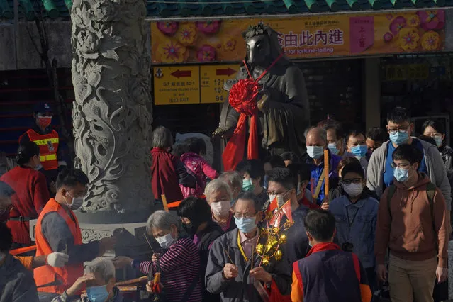 Worshippers wearing face masks to protect against the spread of the coronavirus, queue beside the statue of ox as they pray at the Wong Tai Sin Temple, in Hong Kong, Friday, February 12, 2021 to celebrate the Lunar New Year which marks the Year of the Ox in the Chinese zodiac. (Photo by Kin Cheung/AP Photo)