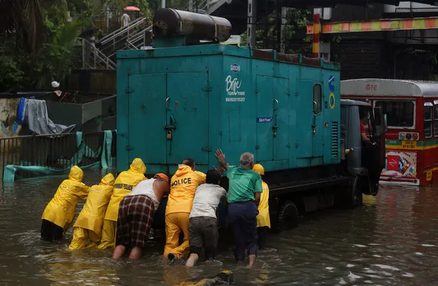 Police personnel and volunteers push a generator truck through a water-logged street after heavy rains in Mumbai June 25, 2018. India' s monsoon season runs from June to September. (Photo by Francis Mascarenhas/Reuters)