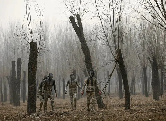 Models, painted in camouflage colours to blend in with the background, take a walk after practising for posing for Chinese artist Liu Bolin's artwork “Dongji”, or Winter Solstice, on the second day after China's capital Beijing issued its second ever “red alert” for air pollution, in Beijing, China, December 20, 2015. (Photo by Kim Kyung-Hoon/Reuters)