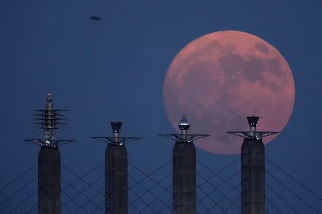 The waxing gibbous moon rises behind sculptures on top of support pylons at Bartle Hall convention center Sunday, July 2, 2023, in Kansas City, Mo. The buck moon will be full on Monday, July 3 and will be the first of four super moons to rise in 2023. (Photo by Charlie Riedel/AP Photo)