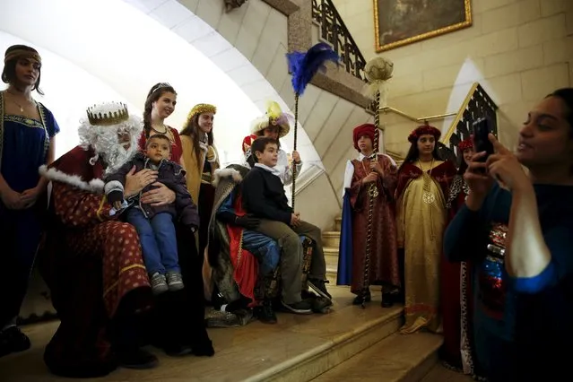 Children have their picture taken on the lap of volunteers dressed as the Three Wise Men during a distribution of free toys for low-income families at Almudena Cathedral in Madrid, Spain, December 22, 2015. (Photo by Susana Vera/Reuters)