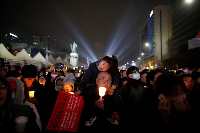 A girl rests on her father's shoulder as they march toward the Presidential Blue House during a protest calling South Korean President Park Geun-hye to step down in Seoul, South Korea, November 19, 2016. (Photo by Kim Hong-Ji/Reuters)