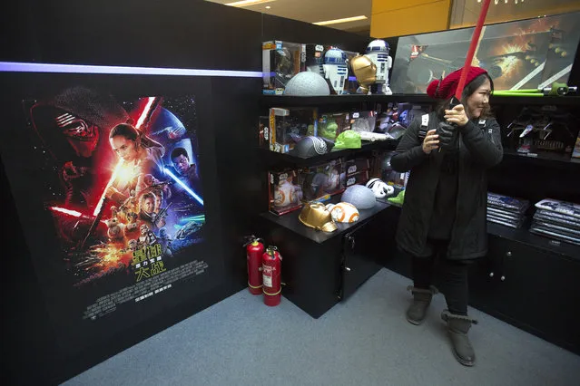 A woman poses for a smartphone photo with a lightsaber at a Star Wars merchandise shop at a shopping mall in Beijing, Saturday, January 9, 2016. The record-breaking "Star Wars" opened Saturday in China, where it is far from certain to draw in enough moviegoers to knock off "Avatar" as the world's all-time biggest grossing movie. (Photo by Mark Schiefelbein/AP Photo)