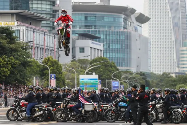 A rider jumps a motorbike over a group of participants during the Malaysia National Day 2023 celebrations in Putrajaya, Malaysia, 31 August 2023. National Day celebrations were held at the Independence Square to mark the 66th anniversary of independence from Britain, which occured on 31 August 1957. (Photo by Fazry Ismail/EPA)
