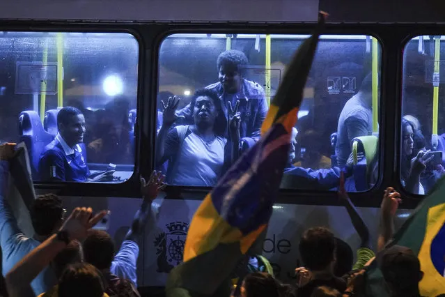 Supporters of Jair Bolsonaro, presidential candidate with the Social Liberal Party celebrate in a bus, in front of his house in Rio de Janeiro, Brazil, Sunday, October 7, 2018.  Official results showed that Fernando Haddad of the Workers' Party will face Jair Bolsonaro, the far-right congressman in a second-round vote. (Photo by Ricardo Borges/AP Photo)