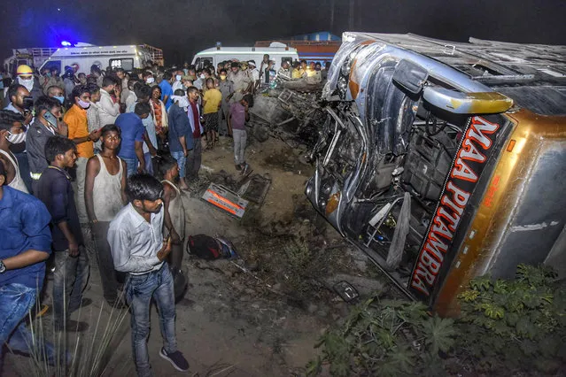 Onlookers gather near the wreckage after a bus carrying migrant workers after the lifting of coronavirus restrictions hit a delivery van on a highway near Kanpur, Uttar Pradesh state, India, Tuesday, June 8, 2021. More than a dozen people were killed. (Photo by AP Photo/Stringer)