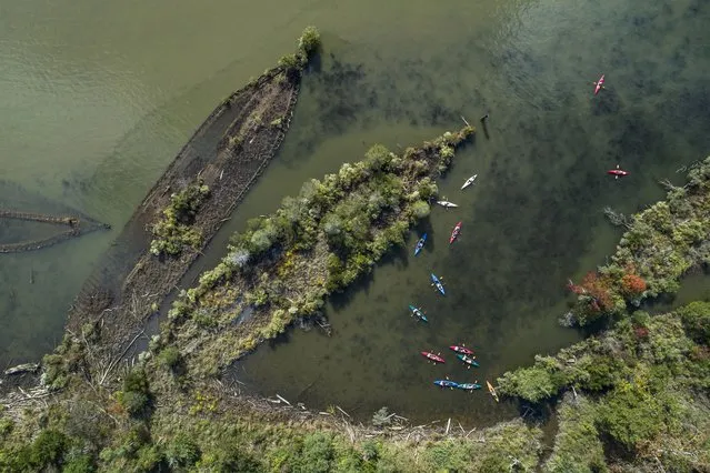 An image made with a drone shows kayakers paddling by the wooden hulls of sunken ships, many from WW1, in the Mallows Bay-Potomac River National Marine Sanctuary near Nanjemoy, Maryland, USA, 30 September 2023. Known as the “Ghost Fleet of the Potomac”, the boats were beached and burned after the war. (Photo by Jim Lo Scalzo/EPA)