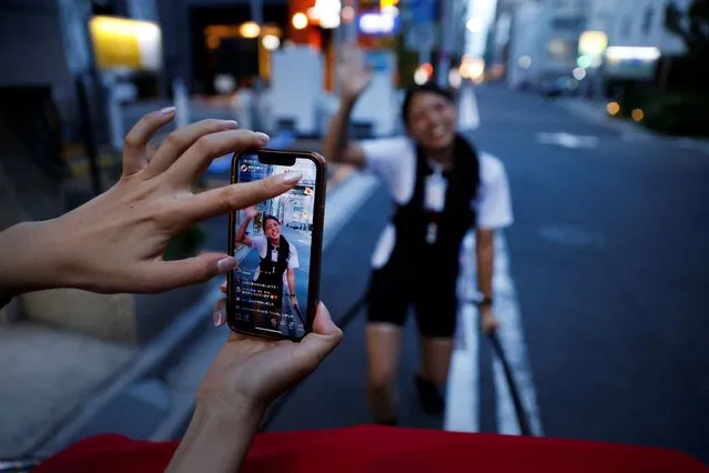 Rickshaw drivers Akina Suzuki (right), 19, and Misato Otoshi, 30, live stream on social media to promote their activities, at the Asakusa district in Tokyo, Japan on August 17, 2023. Otoshi is one of a handful of women who have chosen to pull rickshaws in Tokyo with less than 10 per cent of all applicants getting a job offer. “Even though it’s considered to be men's jobs, I thought it would be fun if I, a woman, could also do it”, she said. “I thought that being something out of the ordinary would be a strength for me”. (Photo by Issei Kato/Reuters)